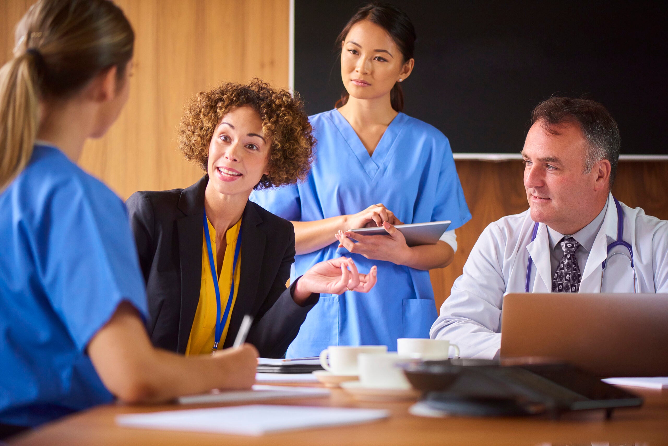 A hospital administrator talking to health professionals in a board room
