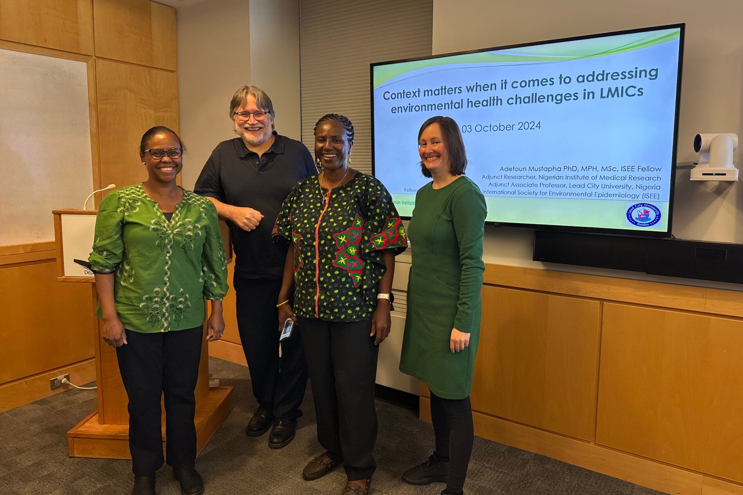 Tamarra James-Todd, Gary Adamkiewicz, Adetoun Mustapha, and Sarah Unninayar in front of Dr. Mustapha's slides
