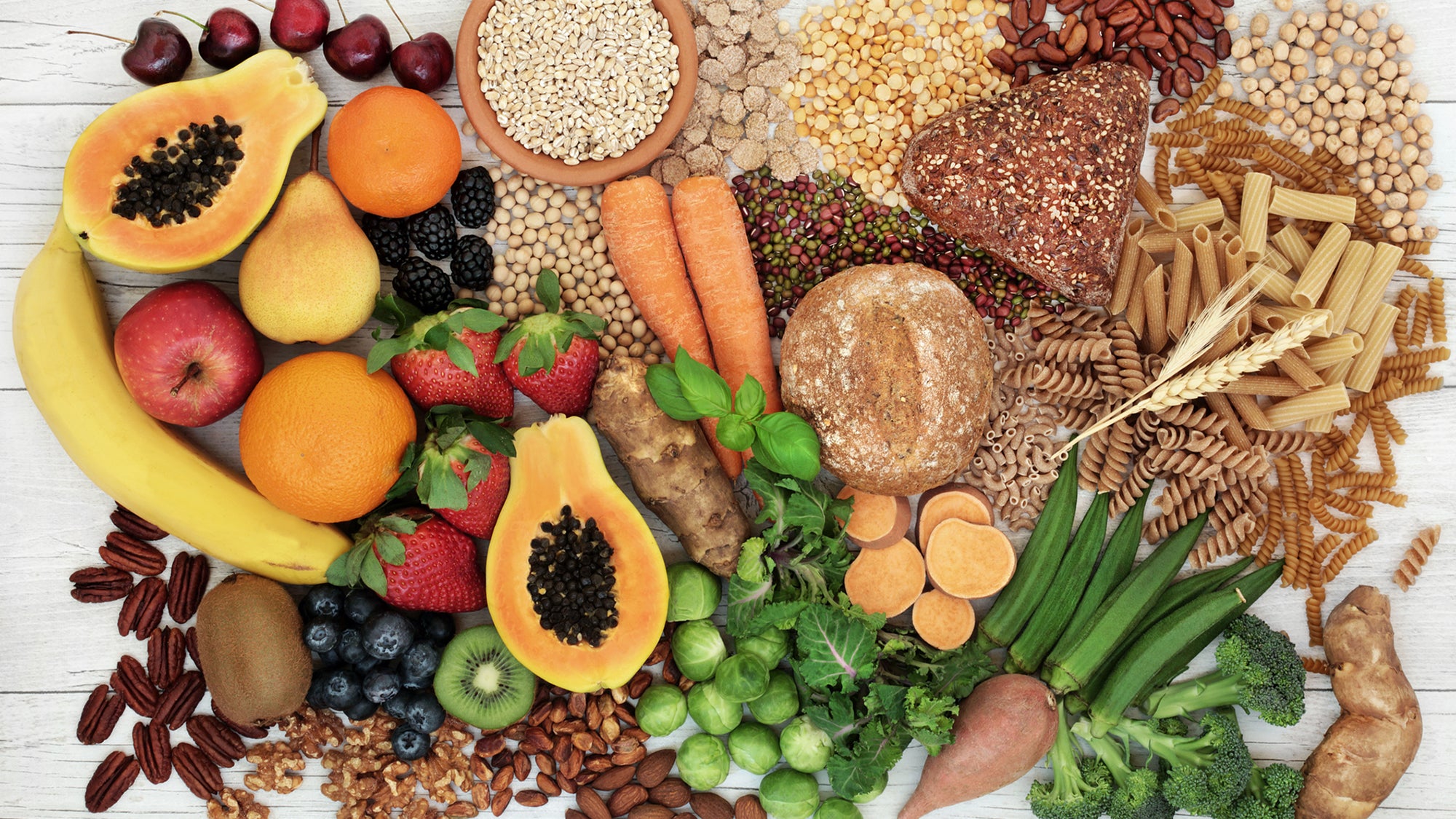 Food with high fiber content for a healthy diet with fruit, vegetables, whole wheat bread, pasta, nuts, legumes, grains and cereals. High in antioxidants, anthocyanins, vitamins and omega 3 fatty acid. Rustic background top view.