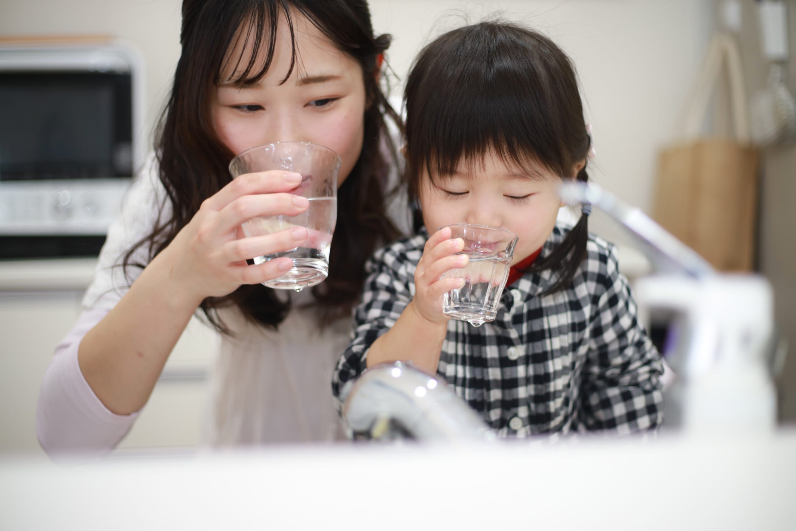 Mom and young daughter drinking glasses of water